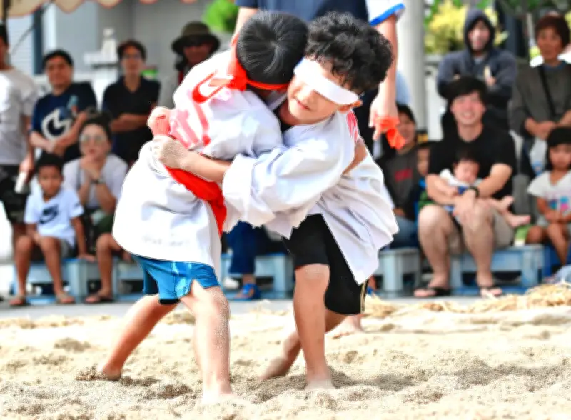 塩屋湾のウンガミ奉納角力で鉢巻きが下がり目隠しに　会場ほっこり