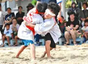 塩屋湾のウンガミ奉納角力で鉢巻きが下がり目隠しに　会場ほっこり